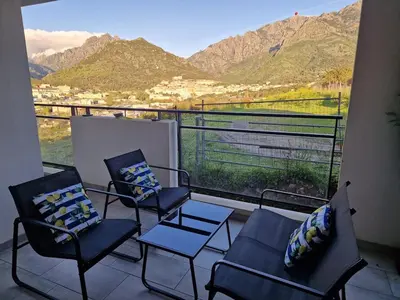 a balcony with chairs and a view of a mountain at Charmant t2 avec terrasse in Corte
