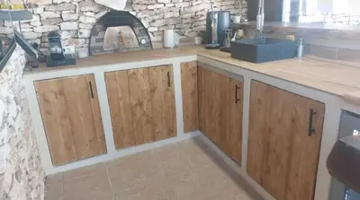 a kitchen with wooden cabinets and a stone fireplace at Casa EliaEmie Bonifacio in Bonifacio