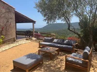 a patio with a couch and chairs and a table at Maison Authentique Corse Vue Mer Panoramique et Nature Sauvage in Zonza