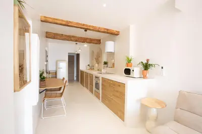 a kitchen with white walls and wooden cabinets at Sublime, hyper-centre d'Ajaccio, avec Spa, Sauna, Vue mer & Plage à 3min in Ajaccio