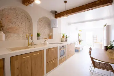 a kitchen with wooden cabinets and a sink and a table at Sublime, hyper-centre d'Ajaccio, avec Spa, Sauna, Vue mer & Plage à 3min in Ajaccio