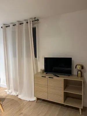 a living room with a television on a dresser with curtains at Casa CARLU-MARIA IV in Corte