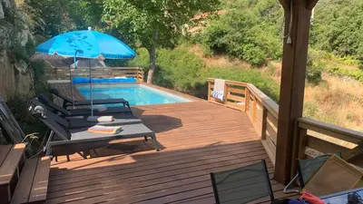 a wooden deck with a pool and an umbrella at U citraghju in Feliceto