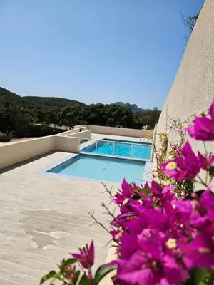 a swimming pool with purple flowers in front of it at Padolo - 5min du Port de Bonifacio in Bonifacio