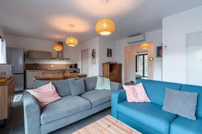 a living room with a blue couch and a kitchen at Padolo - 5min du Port de Bonifacio in Bonifacio