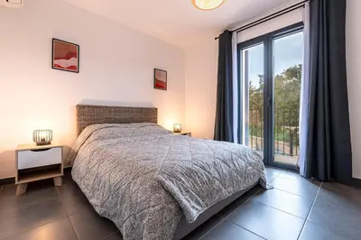 a bedroom with a bed and a large window at Padolo - 5min du Port de Bonifacio in Bonifacio