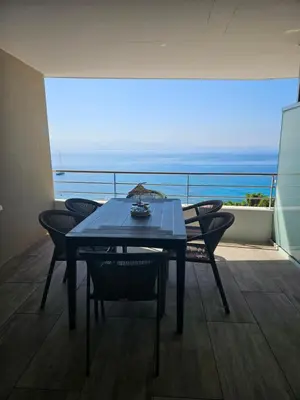 a table and chairs on a balcony with a view of the ocean at Chez Vicky, superbe appartement avec parking privé piscine et vue exceptionnelle in Ajaccio