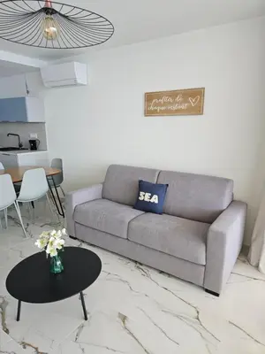 a living room with a couch and a table at Chez Vicky, superbe appartement avec parking privé piscine et vue exceptionnelle in Ajaccio