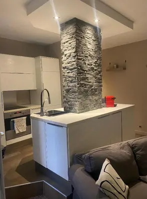 a kitchen with a stone stove and a couch at T2 pied dans l eau in Ajaccio