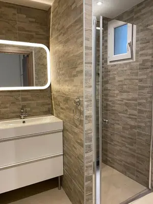 a bathroom with a shower and a sink and a mirror at Vacances pieds dans l eau in Casaglione