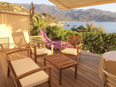 a deck with chairs and tables and a view of the water at Vacances pieds dans l eau in Casaglione