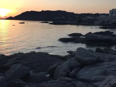 a sunset over a body of water with rocks at Vacances pieds dans l eau in Casaglione
