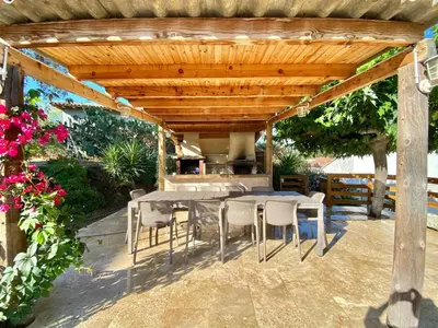 a patio with a table and chairs under a wooden pergola at Casa Maredda with private pool and large garden in Peri