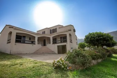 a large white house with a tree in front of it at Casa Maredda with private pool and large garden in Peri