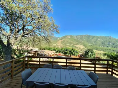a blue table and chairs on a wooden deck with mountains at Casa Maredda with private pool and large garden in Peri