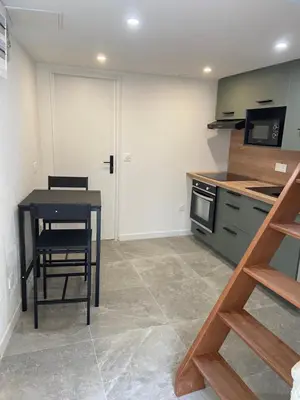 a kitchen with a black table and a table and a microwave at Sottu à a Citadella in Corte