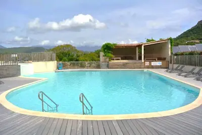 a large swimming pool with chairs on a wooden deck at Villa 3 chambres dans résidence avec piscine in Porto-Vecchio