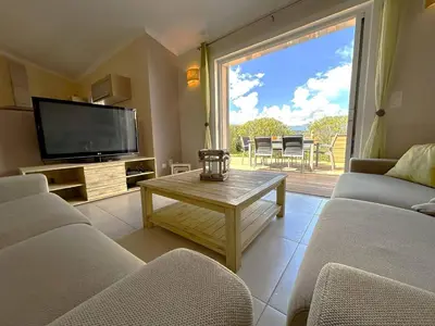 a living room with a couch and a tv and a table at Villa 3 chambres dans résidence avec piscine in Porto-Vecchio