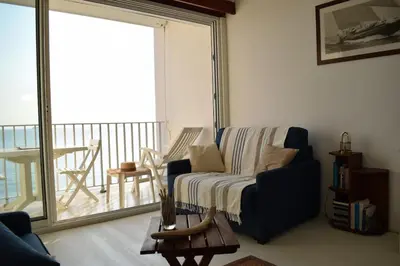a living room with a blue chair and a balcony at Merveilleux, sur la plage et accès direct à la mer in Olmeto