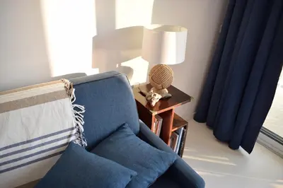 a living room with a blue chair and a lamp at Merveilleux, sur la plage et accès direct à la mer in Olmeto