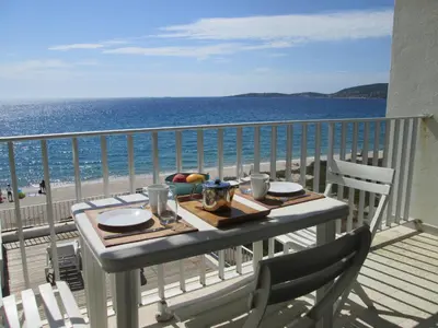 a table on a balcony with a view of the beach at Merveilleux, sur la plage et accès direct à la mer in Olmeto