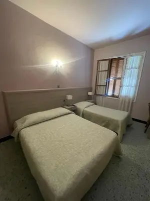 two beds in a room with a cross on the wall at Hotel Les Calanques in Piana