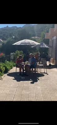 a group of people sitting at a table under an umbrella at Hotel Les Calanques in Piana