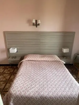 a bedroom with a large bed with two lamps at Hotel Les Calanques in Piana