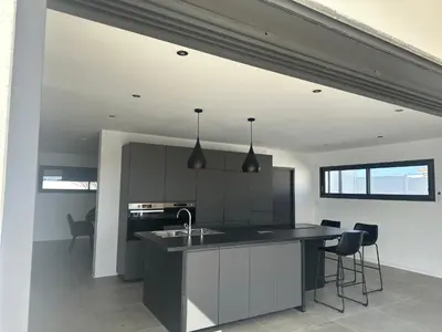 a kitchen with a black and white counter and chairs at Spacieuse villa standing de 220m2 in Aléria