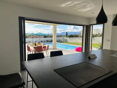 a dining room with a table and a view of a pool at Spacieuse villa standing de 220m2 in Aléria