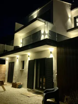 a building with lights on the side of it at night at New quiet upscale air-conditioned villa T2 with heated pool & sea view in Sollacaro