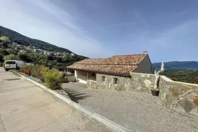 a house with a stone wall next to a road at New quiet upscale air-conditioned villa T2 with heated pool & sea view in Sollacaro