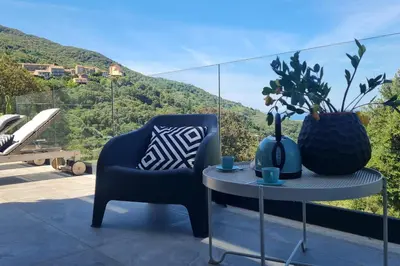 a blue chair and a table on a balcony at New quiet upscale air-conditioned villa T2 with heated pool & sea view in Sollacaro