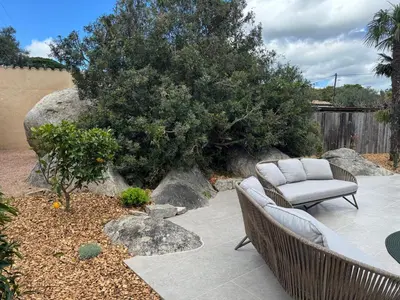 a couch sitting on a patio next to a tree at La petite maison Corse in Porto-Vecchio