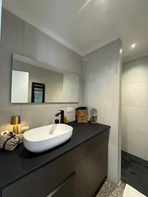 a bathroom with a white sink on a black counter at La petite maison Corse in Porto-Vecchio