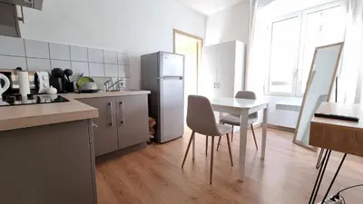 a kitchen with a table and a white refrigerator at Charmant Type 2 hyper centre in Corte
