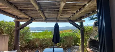 a patio with an umbrella and a view of the water at Mini Villa Santa Giulia double vue mer à 5 min de la plage à pied in Porto-Vecchio