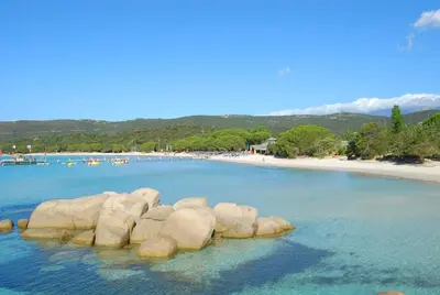 a group of rocks in the water next to a beach at Mini Villa Santa Giulia double vue mer à 5 min de la plage à pied in Porto-Vecchio
