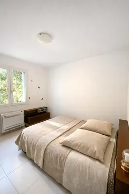 a white bedroom with a large bed and a table at Maison avec vue mer in Penta-di-Casinca