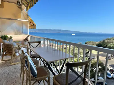 a table and chairs on a balcony with a view of the ocean at Magnifique appartement 3 pièces avec double vue mer in Ajaccio