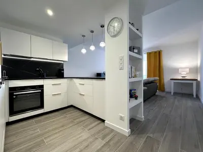 a kitchen with white cabinets and a clock on a wall at Magnifique appartement 3 pièces avec double vue mer in Ajaccio