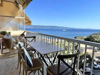 a table and chairs on a balcony with a view of the ocean at Magnifique appartement 3 pièces avec double vue mer in Ajaccio