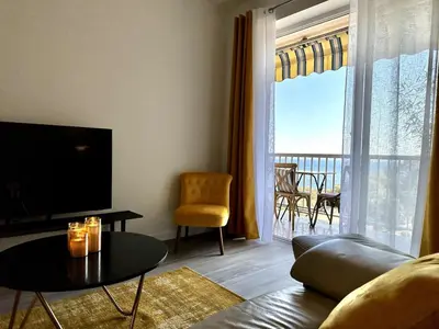 a living room with a couch and a television and a table at Magnifique appartement 3 pièces avec double vue mer in Ajaccio