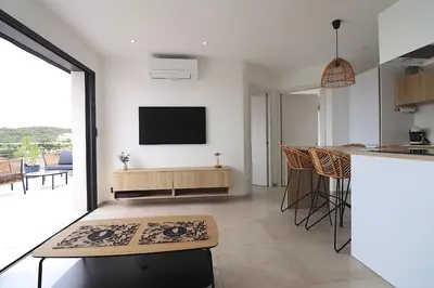 a kitchen and living room with a television on the wall at T3 Le Bohème au Villas Acum - Domaine de Standing avec Vue Mer & Excellente situation géographique in Grosseto-Prugna