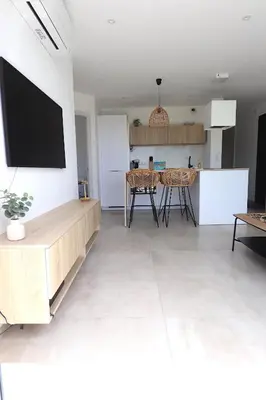a kitchen and a living room with a tv on a wall at T3 Le Bohème au Villas Acum - Domaine de Standing avec Vue Mer & Excellente situation géographique in Grosseto-Prugna