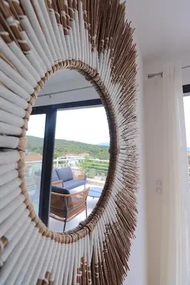 a circular mirror in a room with a chair at T3 Le Bohème au Villas Acum - Domaine de Standing avec Vue Mer & Excellente situation géographique in Grosseto-Prugna