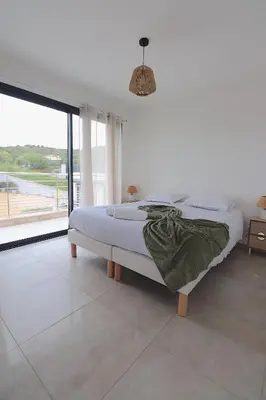 a bed in a bedroom with a large window at T3 Le Bohème au Villas Acum - Domaine de Standing avec Vue Mer & Excellente situation géographique in Grosseto-Prugna