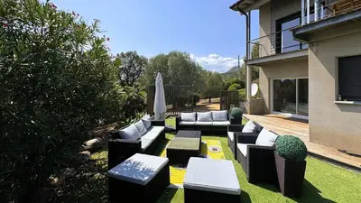 a garden with couches and an umbrella on the grass at Villa Dalenassara, 14 pers, piscine chauffée, 2 min plage en voiture in Olmucciu