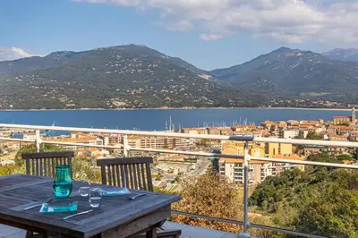 a wooden table on a balcony with a view of a city at monte barbatu in Propriano