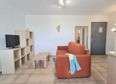 a living room with a orange chair and a tv at Villas MELODY - Appartement climatisé 4/6 pers in Santa-Maria-Poggio